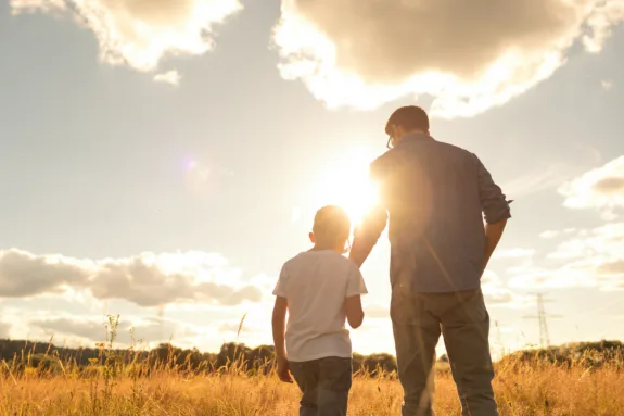 Father and son bonding and watching beautiful sunset together.