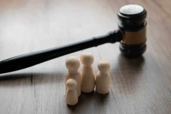 A gavel and four wooden figurines representing a family on a table.